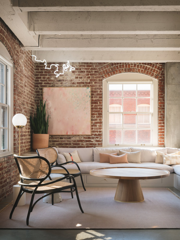Toàn bộ phòng khách bên ô cửa đầy nắng ấm được “khoanh vùng” bởi một chiếc sofa góc có ngăn kéo và tấm thảm Kinnasand màu hồng nhạt từ thương hiệu The Future Perfect. 