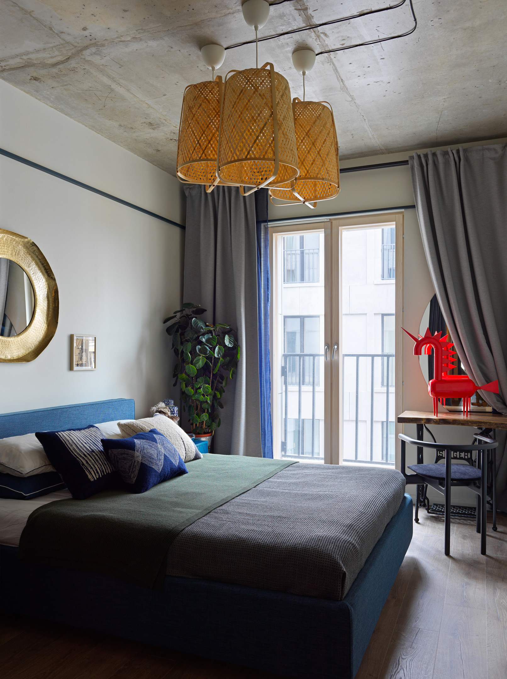 Phòng ngủ dành cho khách có thiết kế nhẹ nhàng hơn về mặt màu sắc. Những gam màu trung tính như xám, xanh lam kết đèn trần mây tre đan mộc mạc và một bộ bàn ghế nhỏ để đọc sách gần cửa sổ.