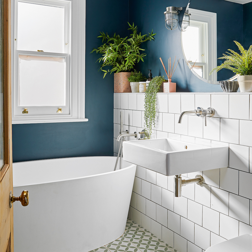 Tường màu xanh lam đậm được sơn mới bổ sung, kết hợp gạch ốp màu trắng tươi sáng tạo nên sự tương phản cho phòng tắm thêm chiều sâu hút mắt.