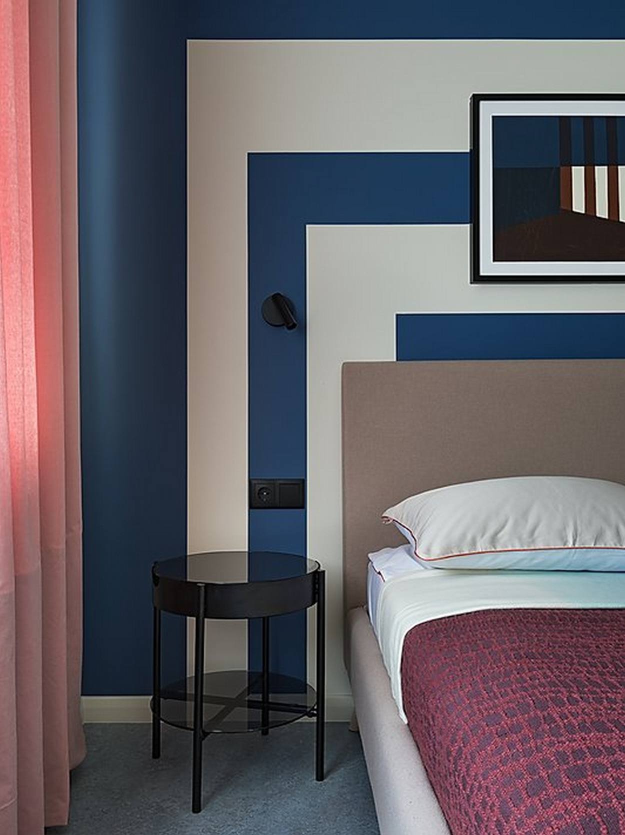 Bức tường đầu giường phòng ngủ được trang trí bằng những khối hình học hình vuông cân xứng, xen kẽ 2 gam màu trắng và xanh lam đậm, vừa để tạo sự khác biệt với các khu vực còn lại vừa tạo cảm giác yên bình, tĩnh tại cho không gian thư giãn.