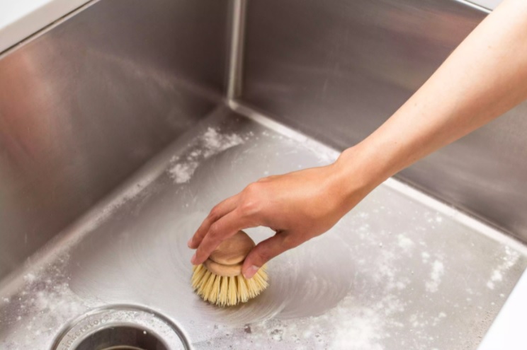 Dùng miếng bọt biển hoặc bàn chải lông mềm để làm sạch bồn rửa theo thớ của thép không gỉ.