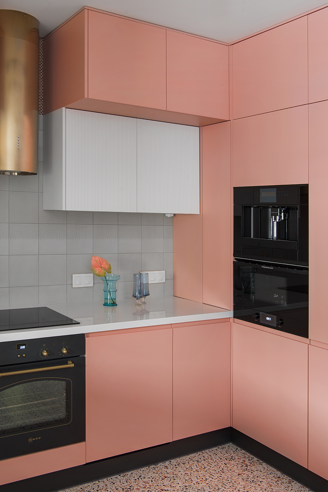 Cấu trúc chữ L là giải pháp hoàn hảo cho những căn hộ có diện tích vừa và nhỏ. Ở đây, sự phối hợp giữa hệ thống tủ lưu trữ  màu hồng ngọt ngào được cân bằng bởi mặt bàn, khu vực backsplash ốp gạch trắng để căn phòng xinh xắn nhưng không quá 'bánh bèo'.