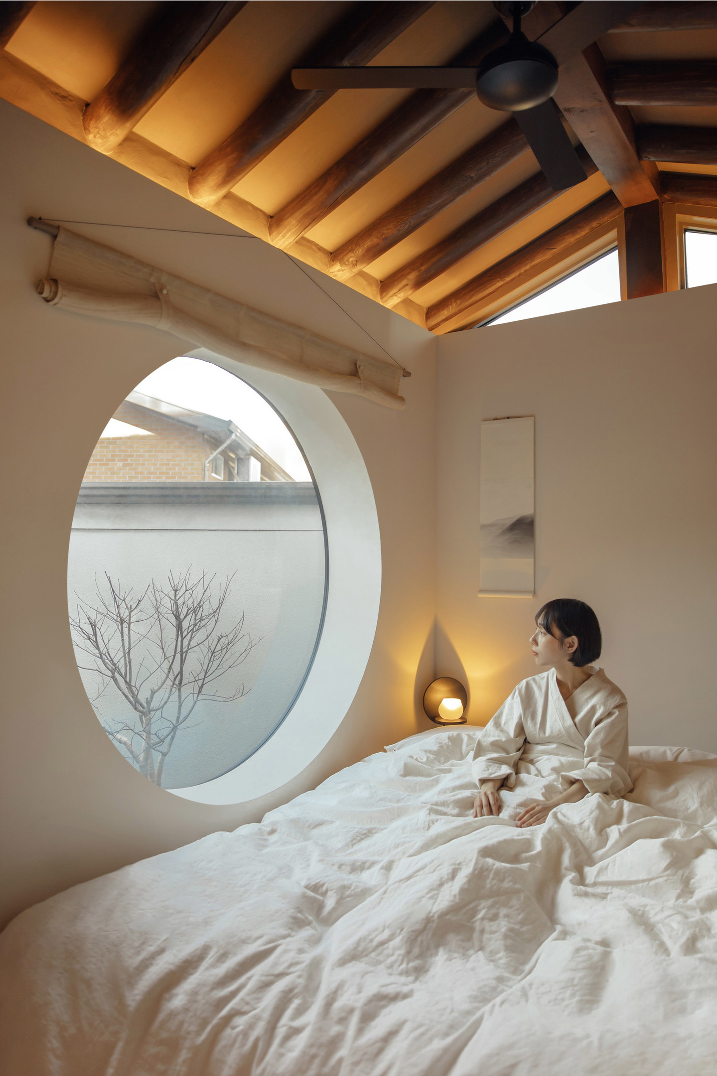 Ngôi nhà tại Seoul (Hàn Quốc) do Z_Lab Studio thiết kế theo phong cách truyền thống. Trần dầm gỗ tối màu tương phản với tường trắng muốt, kết hợp ô cửa kính tròn khiến con người bên trong và thiên nhiên bên ngoài như hòa vào làm một. 