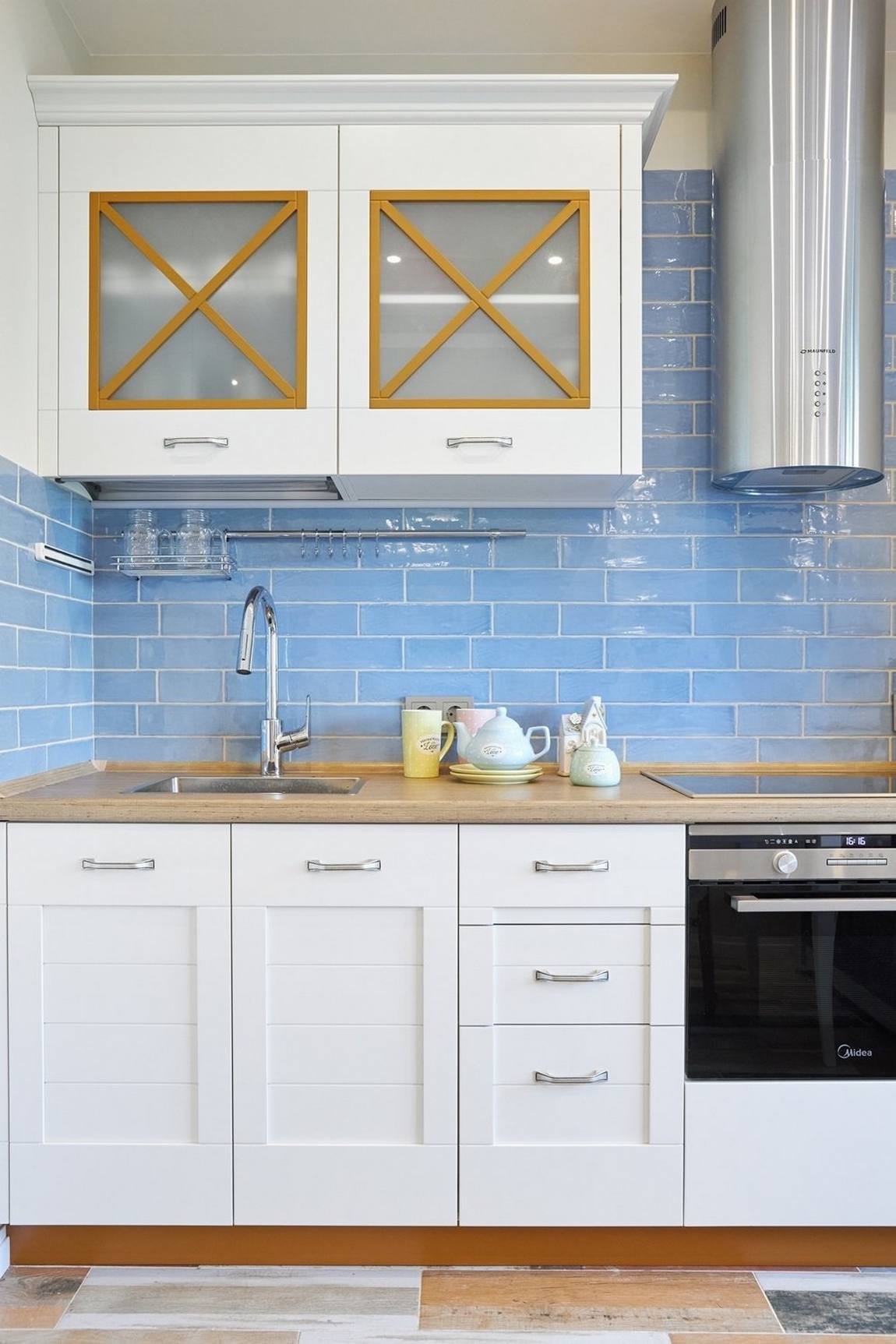 Khu vực backsplash của phòng bếp được ốp gạch màu xanh lam theo kiểu gạch thẻ metro có lớp hoàn thiện sáng bóng, tạo sức hút về màu sắc cũng như phản chiếu ánh sáng lên bề mặt bóng loáng.