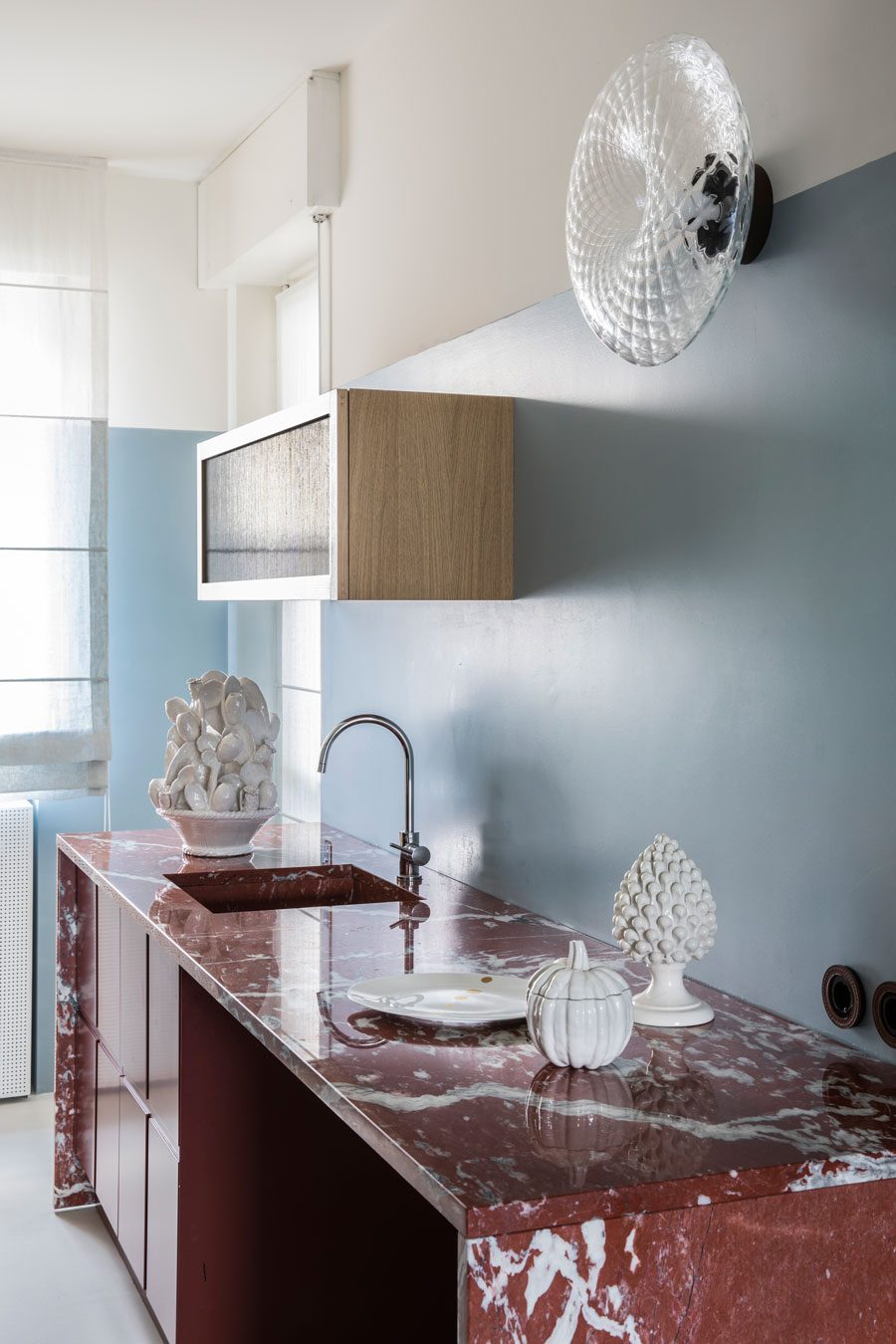 Phòng bếp trong căn hộ của Clara Ceccherini với mặt bếp làm bằng đá cẩm thạch đỏ của Pháp, mang đến vẻ đẹp nồng nàn, quyến rũ. Bên cạnh đó, sắc xanh lam nhạt của màu sơn tường trung hòa lại tạo nên sự dễ chịu cho không gian nấu nướng.