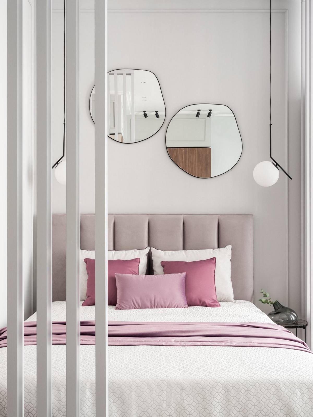 Đầu giường bọc nệm vững chãi với màu xám thanh lịch, phối hợp với bộ chăn ga gối tông trắng và tím tạo sự liên kết về màu sắc với các khu vực còn lại trong căn hộ.