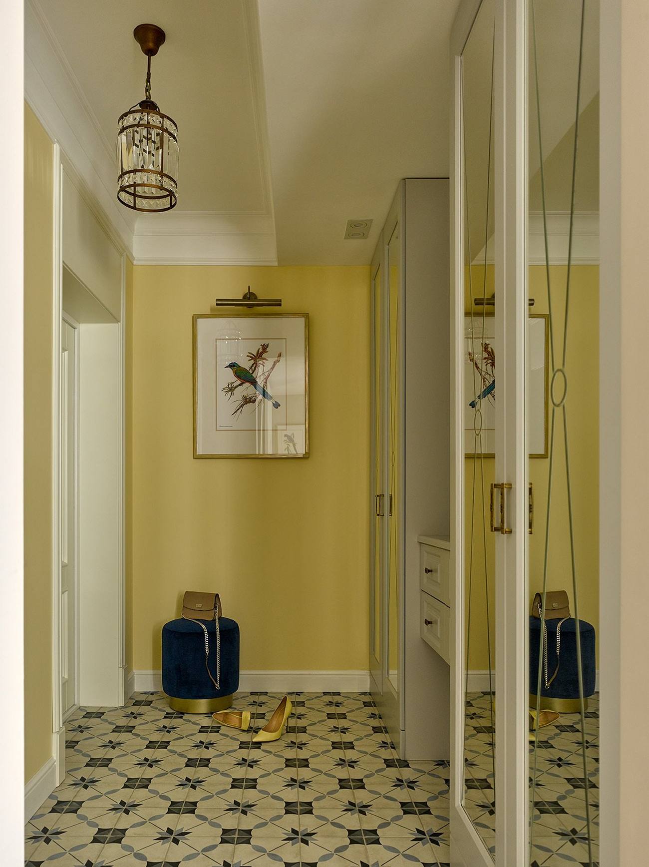 Lối vào căn hộ tràn đầy năng lượng với gam màu vàng trẻ trung của màu sơn tường, phối hợp với sàn nhà lát gạch bông hoa văn cổ điển. Chiếc đèn thả trần ấn tượng cùng bức tranh chú chim nhỏ cho không gian bắt mắt hơn.
