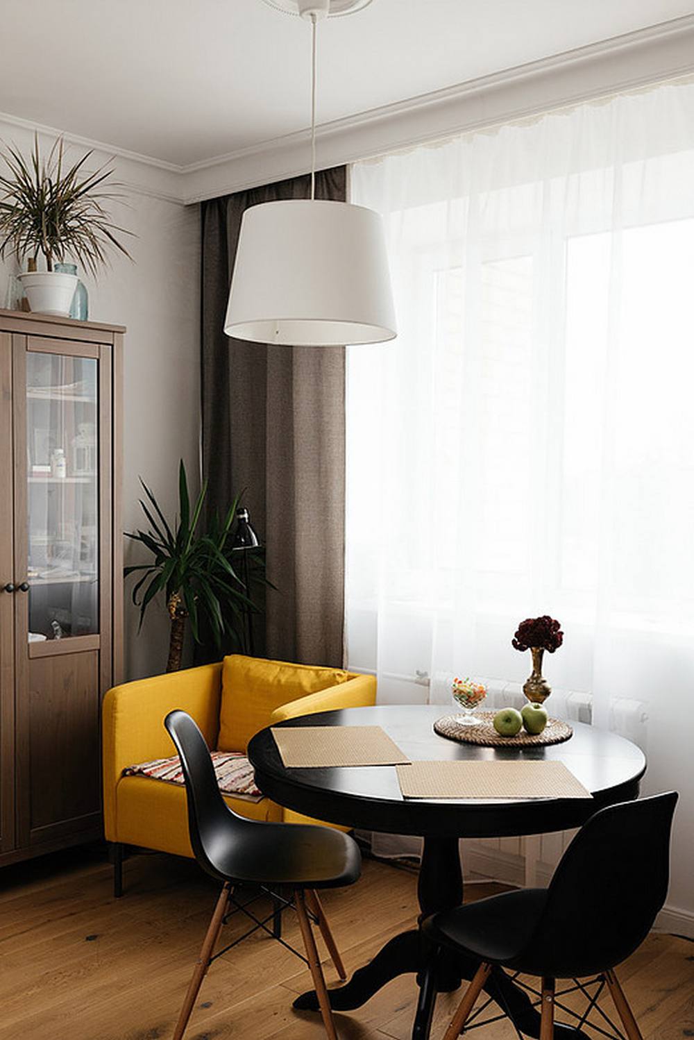 Khu vực ăn uống với bộ bàn ghế tròn màu đen vững chãi. Việc lựa chọn nội thất hình tròn là giải pháp phù hợp cho căn hộ nhỏ, giúp tiết kiệm không gian so với mẫu bàn dài vuông vức. Bên trên là đèn thả trần màu trắng tạo sự tương phản nhẹ nhàng.