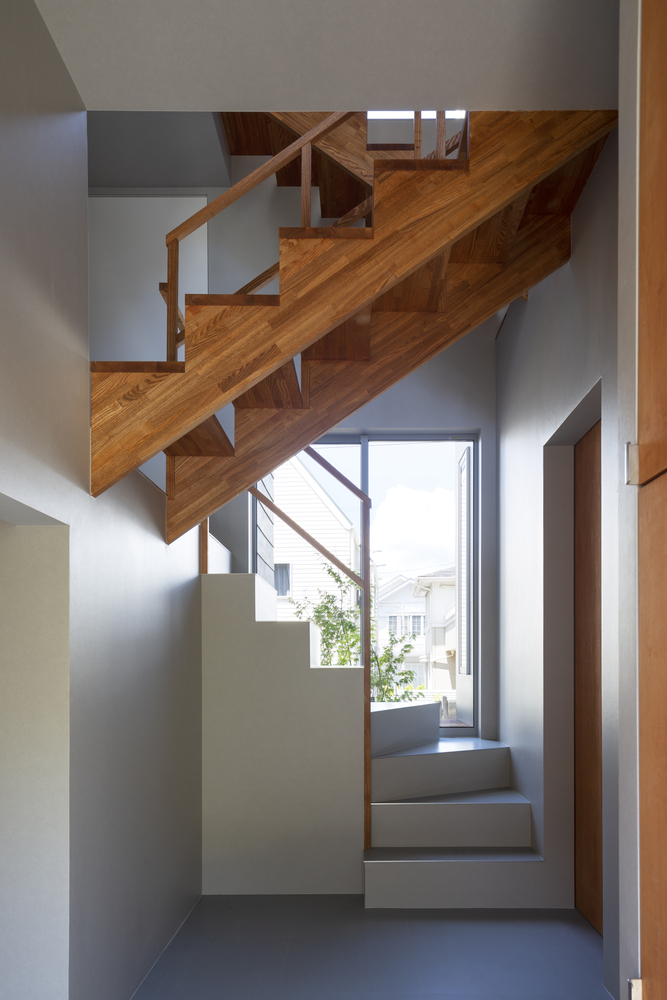 Quang cảnh chụp cầu thang cho phép bạn hình dung về không gian của ngôi nhà từ lệch tầng, với sự xen kẽ của nội thất gỗ tự nhiên trầm ấm và màu trắng tươi sáng.