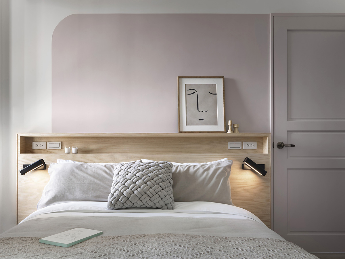 Phòng ngủ của cặp đôi mang bầu không khí thư giãn nhẹ nhàng, khéo léo phối màu sơn tường gồm trắng và hồng phấn. Đầu giường bằng gỗ sáng màu kết hợp không gian lưu trữ cho cái nhìn vững chãi. 