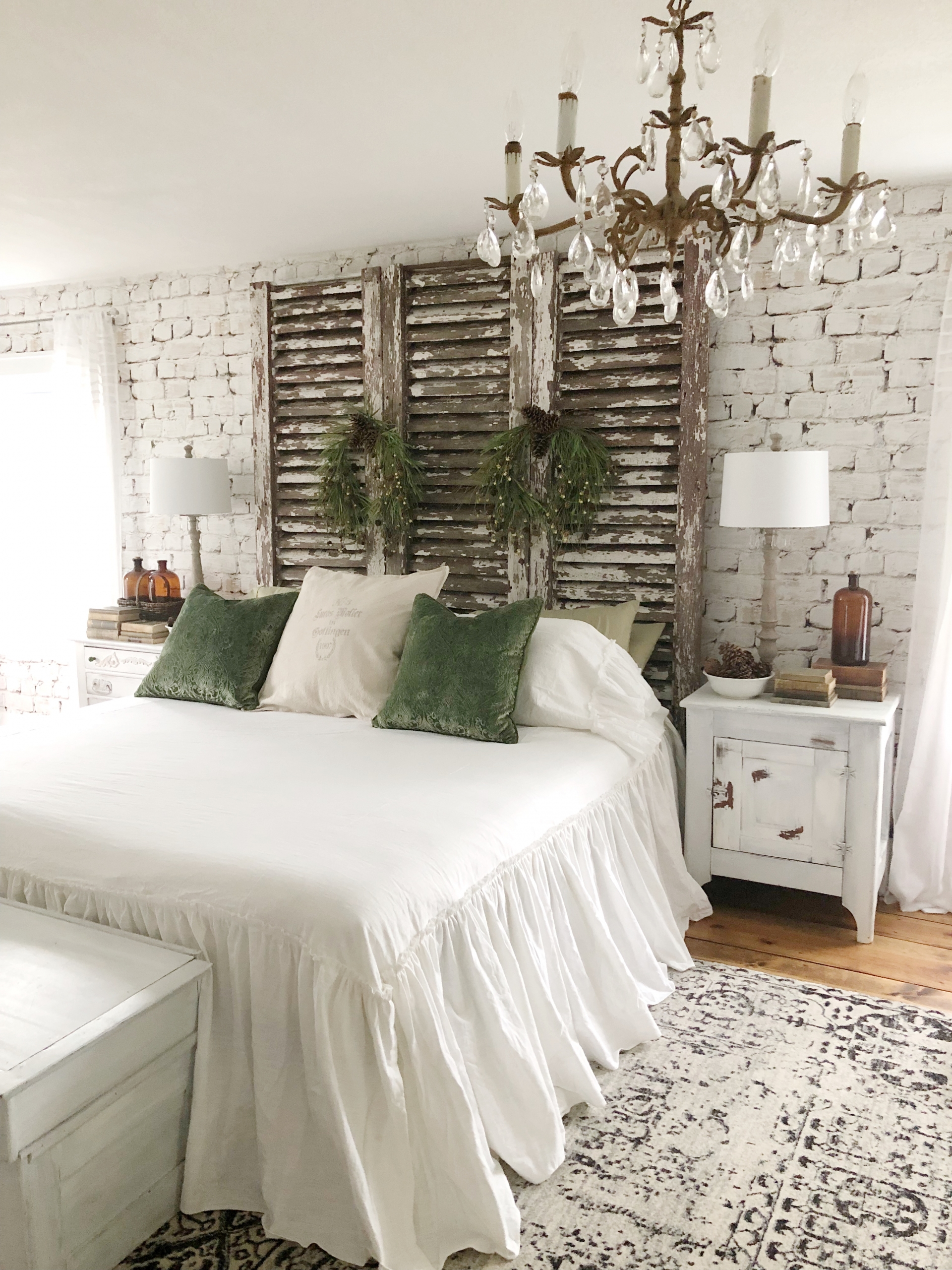 Sự kết hợp giữa bức tường gạch thô lớp với sơn màu trắng và cánh cửa chớp gỗ mộc mạc ở vị trí đầu giường phòng ngủ. Thêm vào chiếc đèn chùm pha lê với kiểu thiết kế những ngọn nến lung linh càng giúp không gian thư giãn thêm phần ấn tượng.