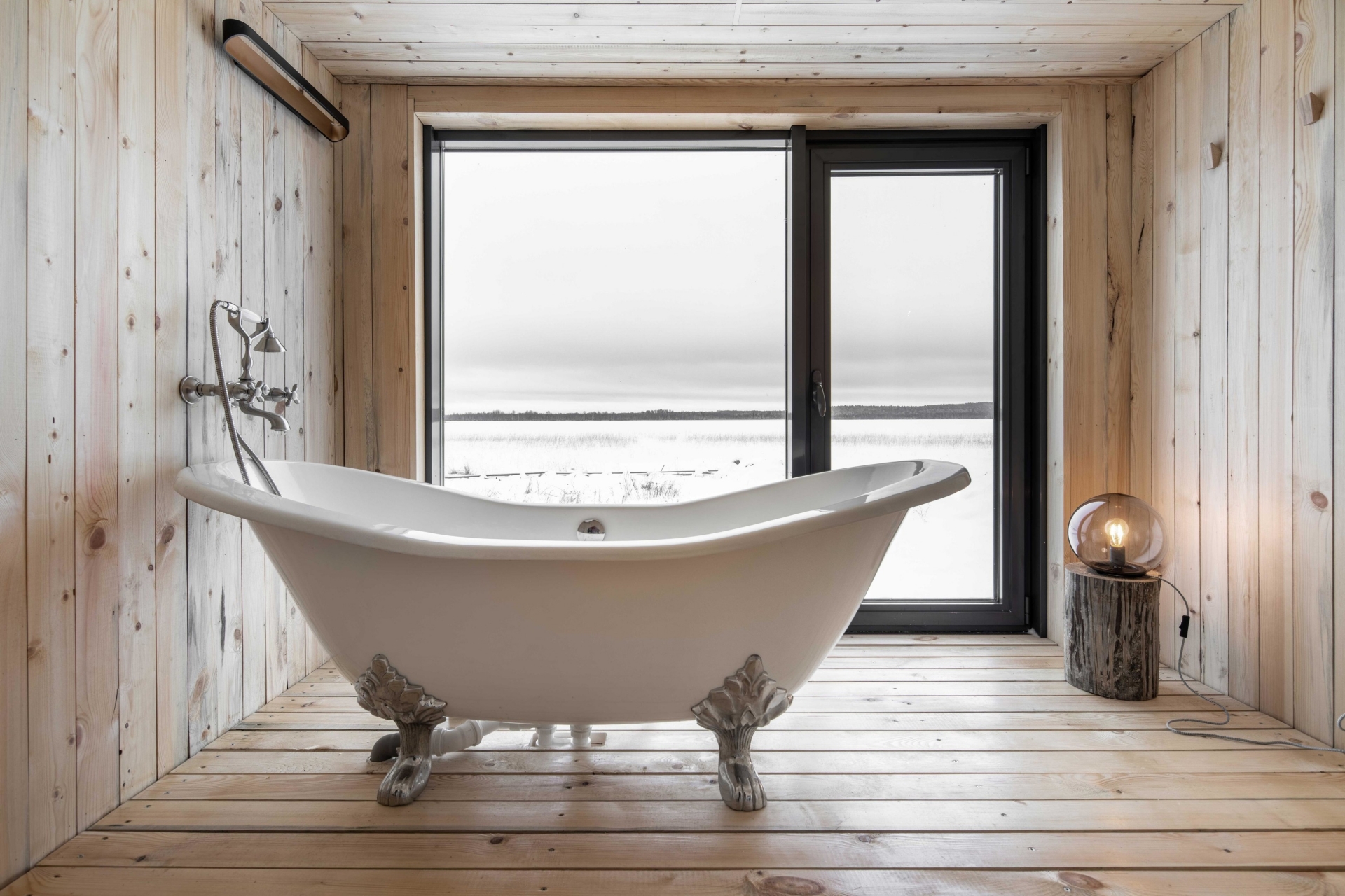 Phòng tắm nằm trong nhà khách vùng ngoại ô Cộng hòa Kareliya do Maya Baklan thiết kế nội thất. Tường, trần và sàn nhà được hoàn thiện bằng ván gỗ mộc mạc như hòa quyện cùng thiên nhiên thoáng đãng bên ngoài.