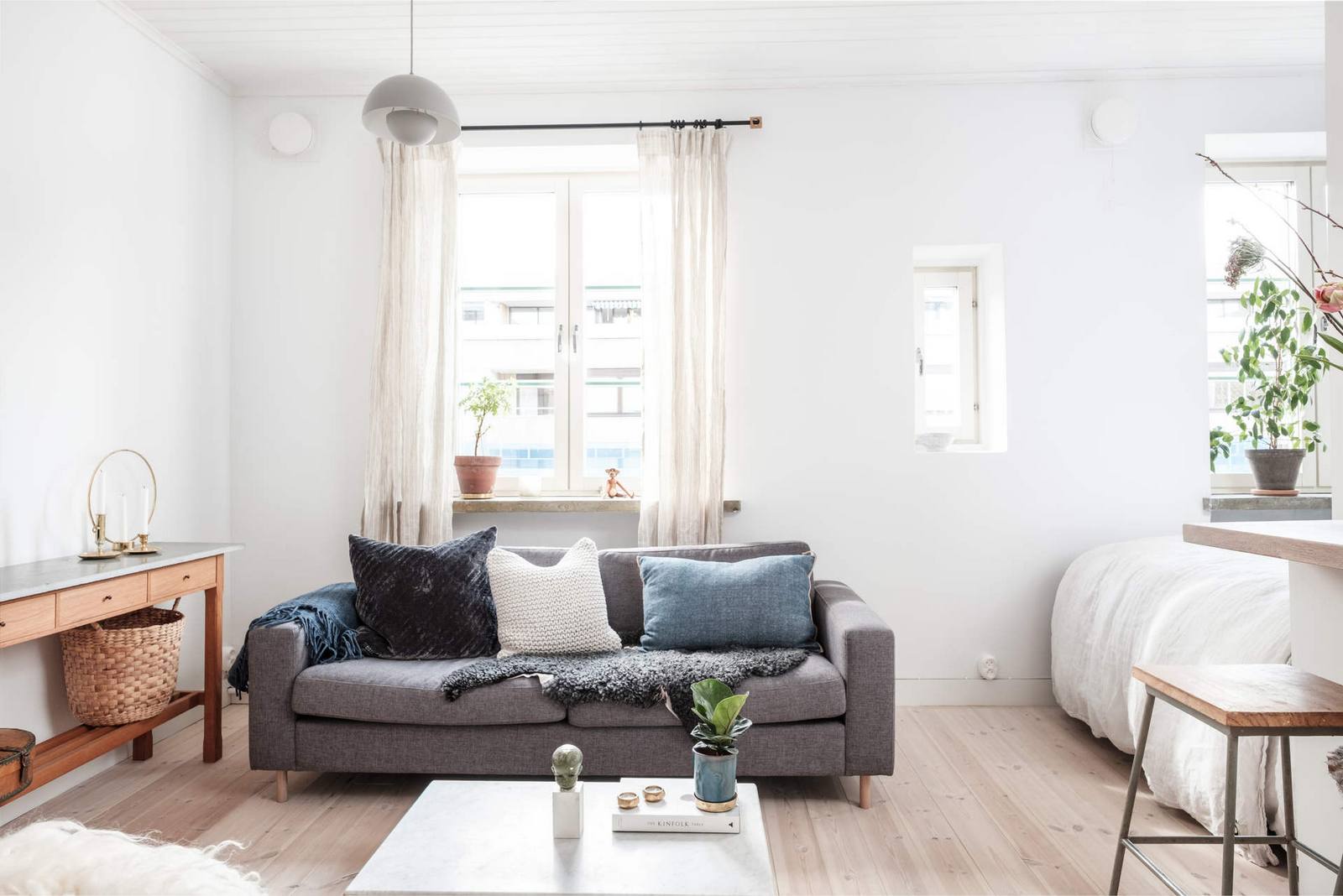Phòng khách xinh xắn với chiếc ghế sofa màu xám, nhấn nhá bằng những chiếc gối tựa lưng êm ái. Chiếc bàn nước màu trắng thiết kế đơn giản, gọn nhẹ, mang phong cách Scandinavian của xứ Bắc Âu.