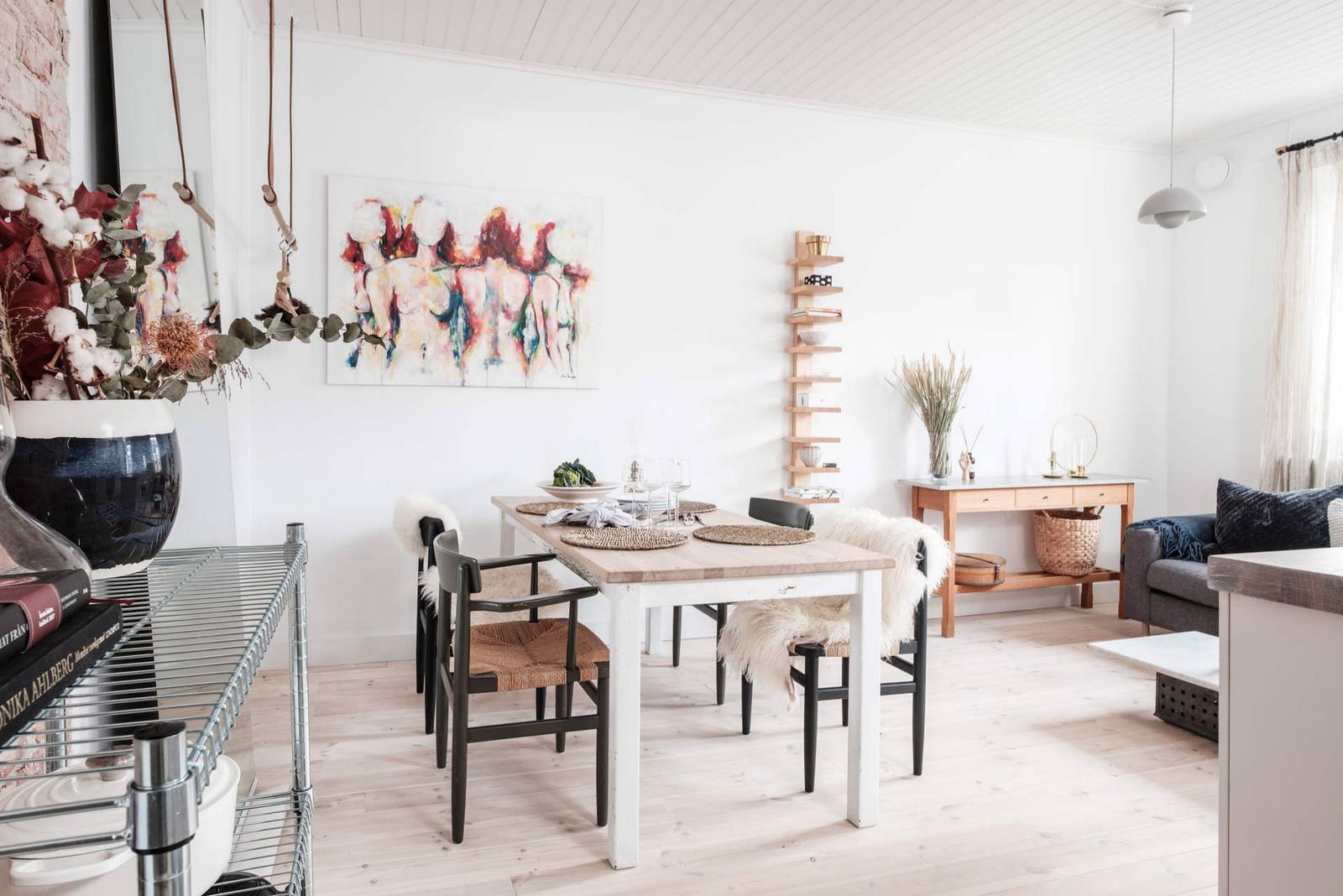 Khu vực ăn uống được bố trí đối diện phòng khách với chiếc bàn ăn ốp gỗ sáng màu, chân bàn sơn trắng tạo sự tương phản nhẹ nhàng với những chiếc ghế màu đen xung quanh nó.