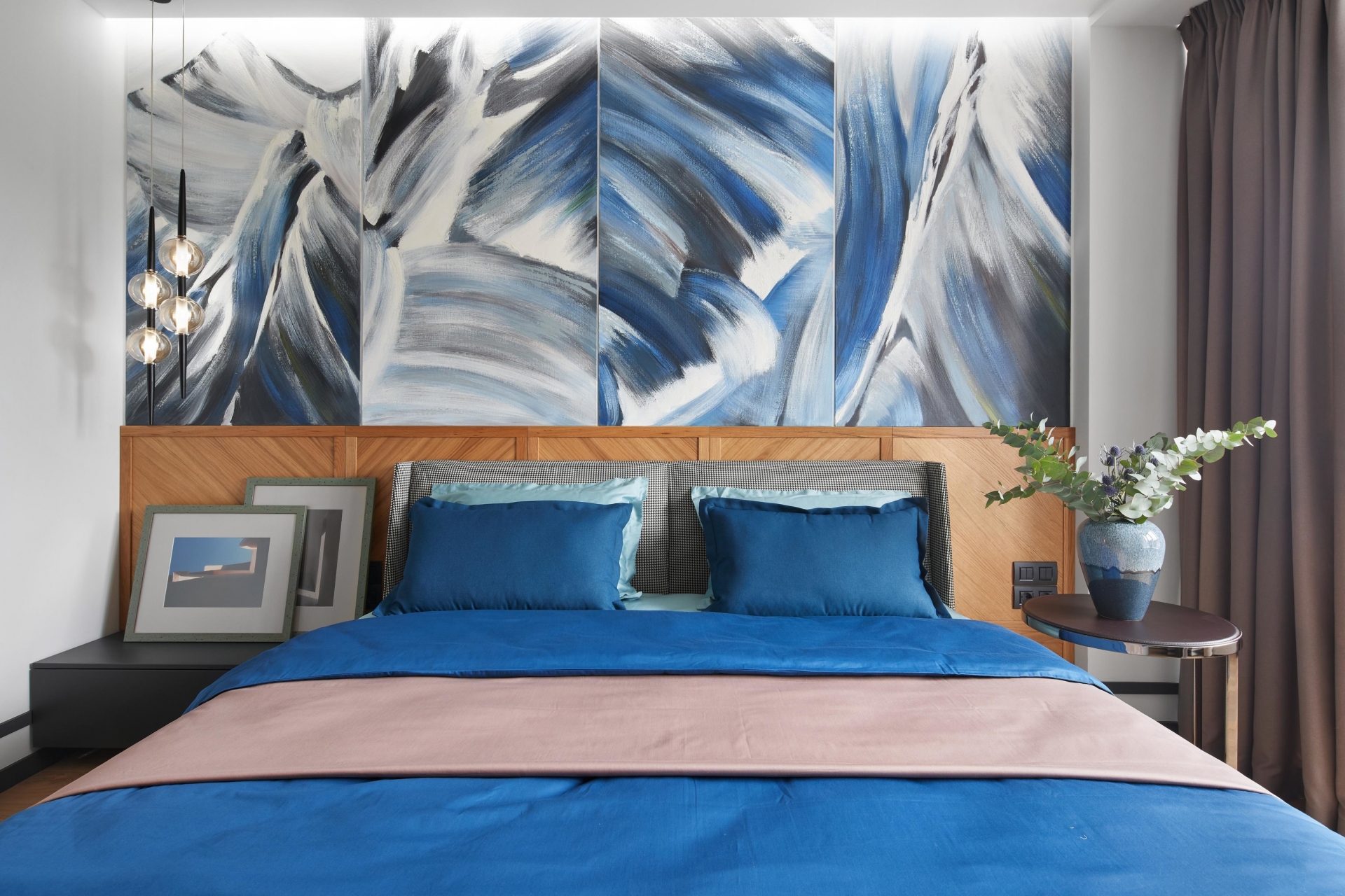 Riêng phòng ngủ được chủ nhân ưu ái hơn khi sử dụng gam màu xanh lam làm điểm nhấn. Đây cũng là căn phòng duy nhất lựa chọn sắc màu trẻ trung để trang trí. Màu xanh lam nhiều sắc thái đậm nhạt, từ bộ chăn ga gối đến bức tranh trừu tượng nổi bật trên nền tường phòng ngủ.