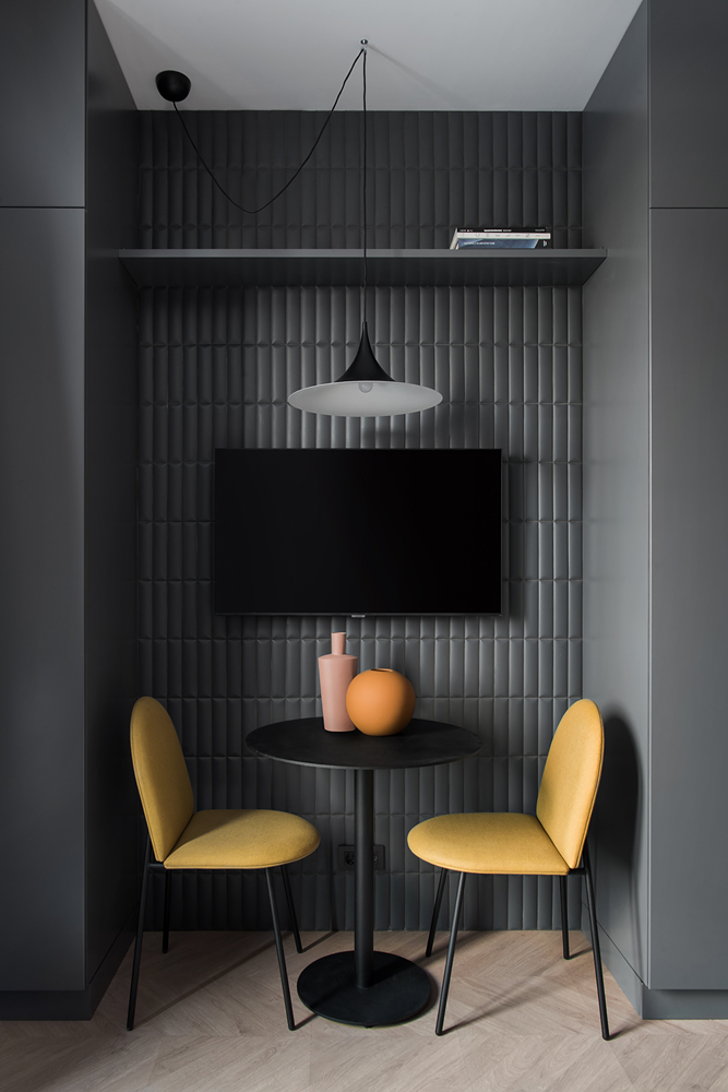 Tận dụng hốc tường sẵn có để bố trí 1 chiếc bàn tròn nhỏ màu đen cùng 2 chiếc ghế vàng mù tạt nổi bật, tạo nên góc ăn uống ấm cúng. 