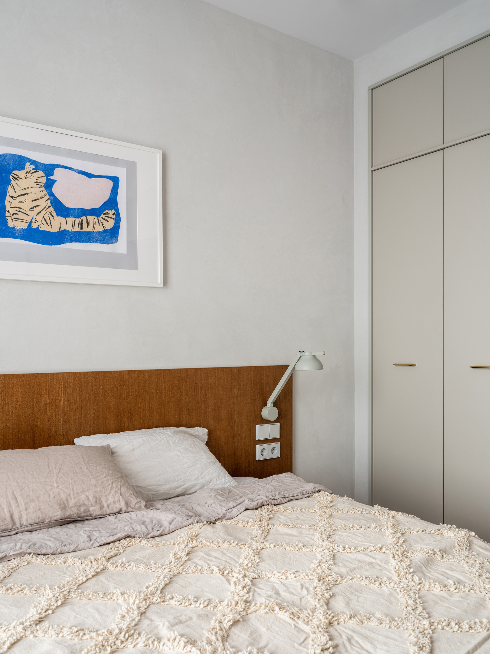Hai chiếc đèn ngủ kết hợp đèn đọc sách gắn đối xứng ở 2 bên đầu giường tạo sự cân đối, hài hòa. Cũng như hành lang lối vào hay phòng làm việc, NTK nội thất cũng tối ưu hóa khả năng lưu trữ trong căn hộ bằng cách sử dụng tủ quần áo kịch trần màu xám trang nhã.