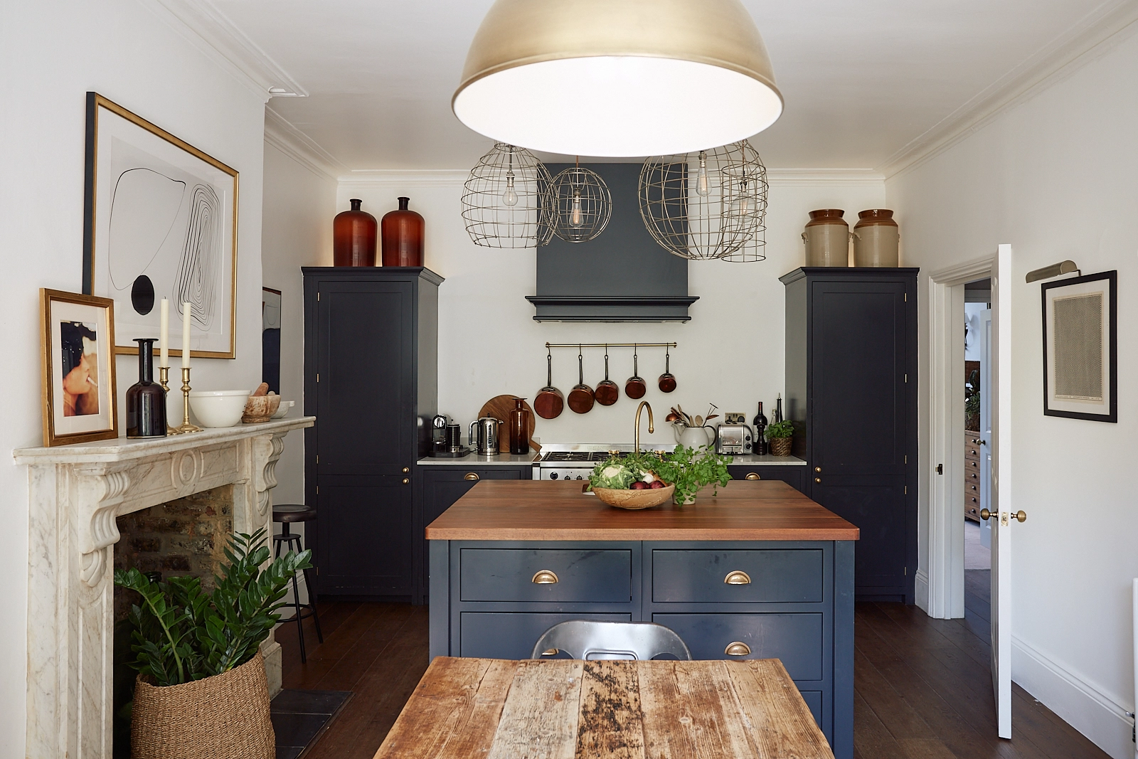 Phòng bếp thiết kế gọn gàng với hệ tủ lưu trữ cân xứng hai bên với màu xanh đậm tạo nét vững chãi và mạnh mẽ. Đảo bếp ở trung tâm sử dụng tone màu xanh có phần nhạt hơn, nổi bật bởi những phần tay nắm mạ vàng đồng.