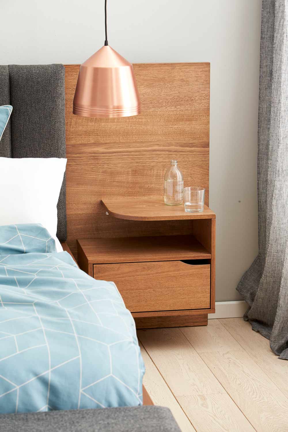 Kiểu táp đầu giường bằng gỗ nối liền với phần đầu giường bọc đệm xám vững chắc, với 3 vị trí có thể tận dụng để lưu trữ và sắp xếp đồ đạc, bao gồm bề mặt trên cùng, tầng giữa và ngăn kéo kín đáo.