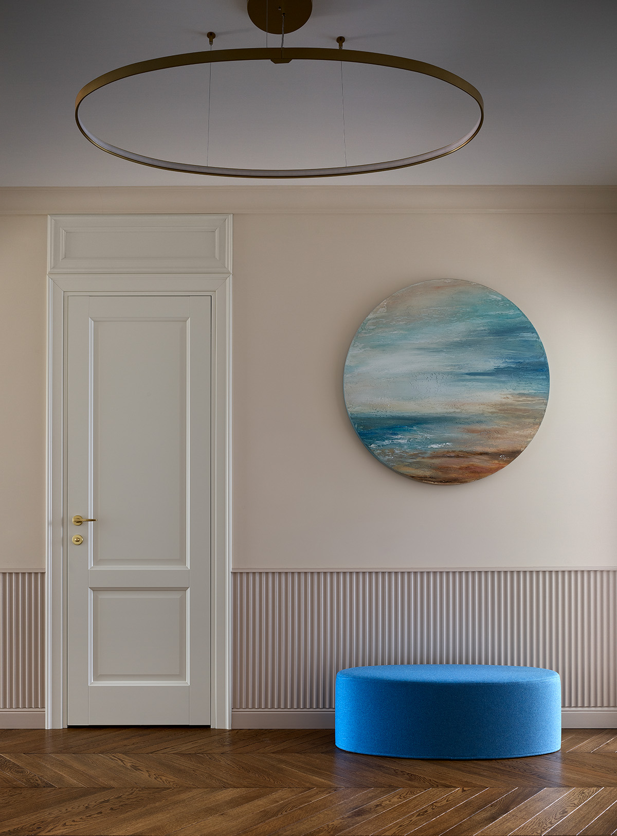 Hành lang lối vào căn hộ đẹp dịu dàng với cánh cửa trắng trên nền tường màu be. Chiếc ghế nghỉ chân hình oval màu xanh lam kết hợp với bức tranh biển cả treo tường của họa sĩ Irina Nuzhdina khiến lòng người lắng lại khi nhìn ngắm.