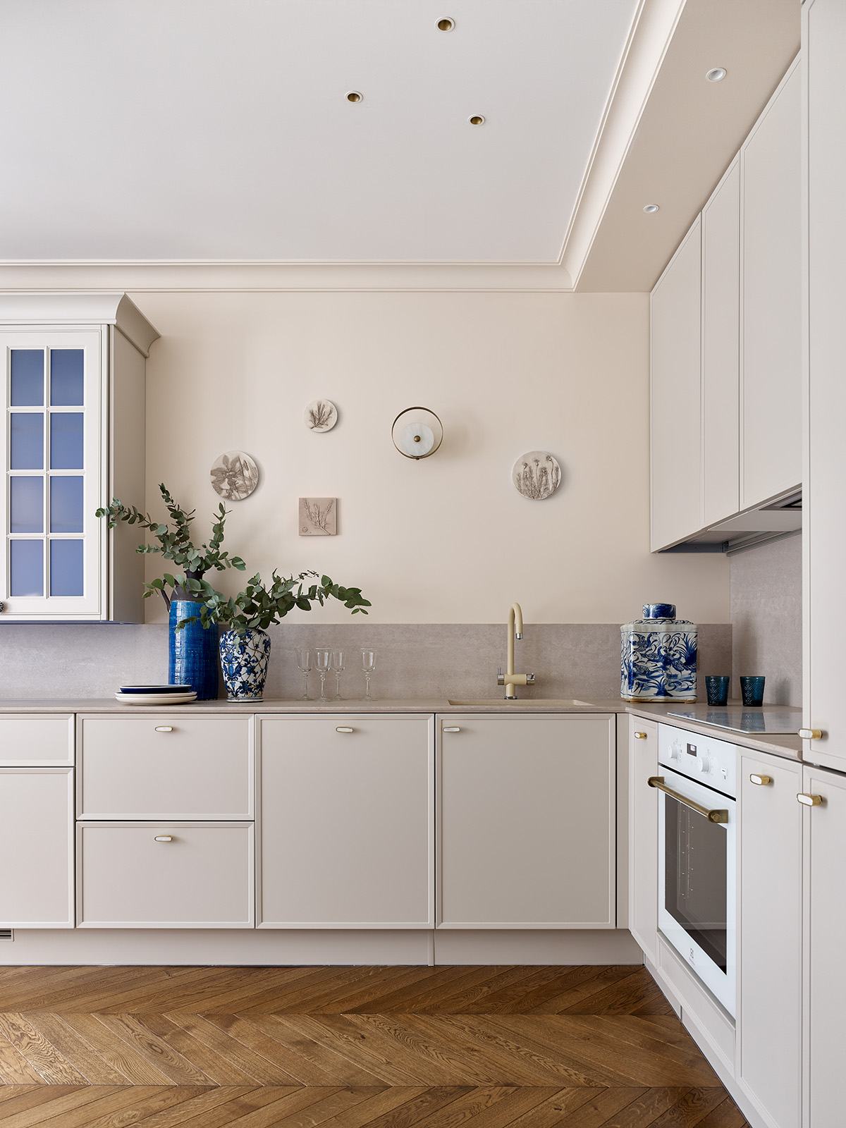 Phòng bếp lựa chọn thiết kế chữ L vừa phù hợp với cấu trúc căn hộ vừa tận dụng không gian hiệu quả. Hệ thống tủ lưu trữ trên - dưới cùng những chi tiết trang trí bằng gốm sứ hoa văn xanh lam hay tranh treo tường cho khu vực nấu nướng trở nên thi vị.