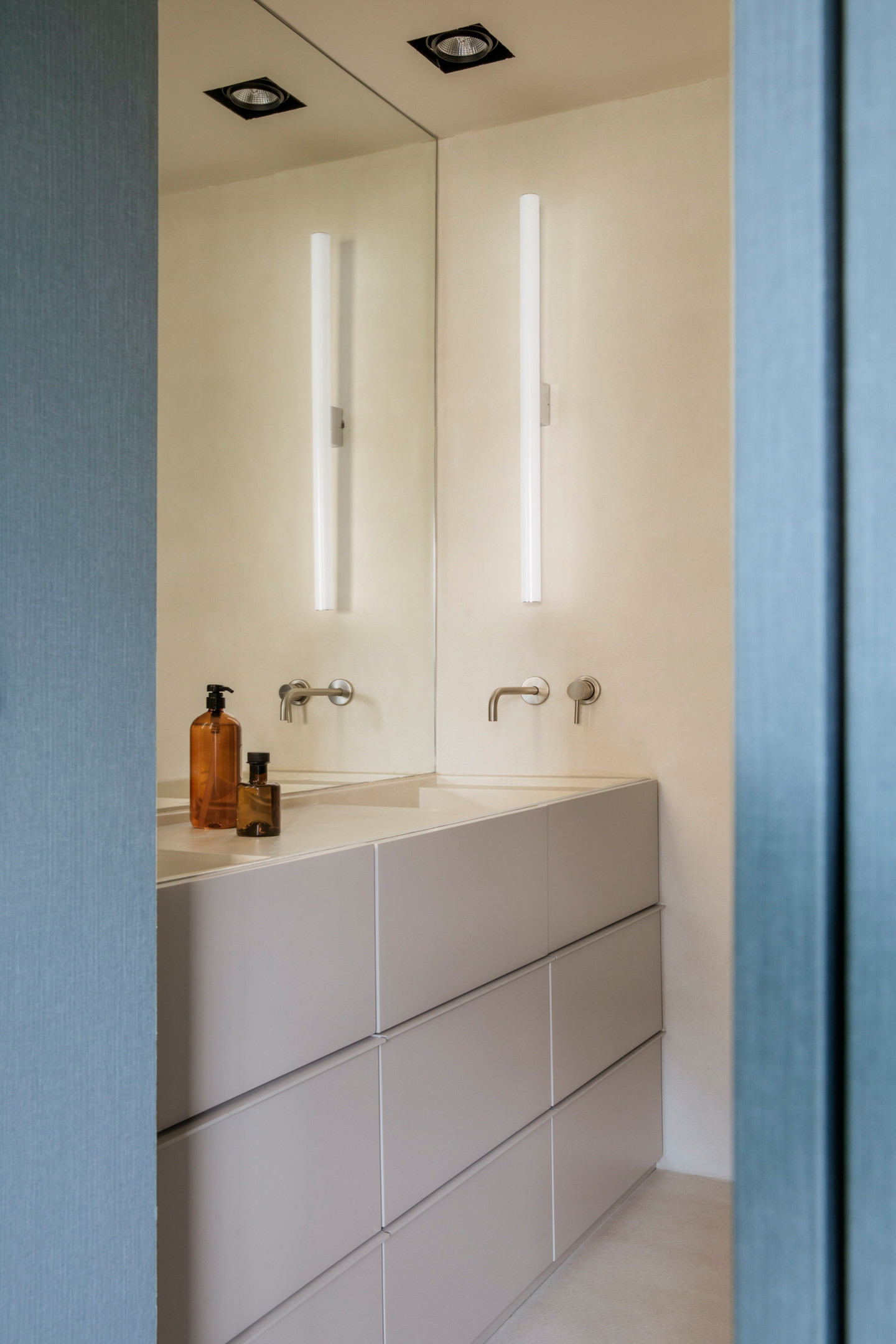 Căn hộ gồm 2 phòng tắm, 1 phòng tắm chính và 1 phòng cho khách đến thăm nhà. Phòng tắm đầu tiên với hệ thống đèn ốp trần và đèn gắn tường bố trí cạnh tấm gương ốp 'full' tường trên bồn rửa cho không gian tươi sáng và 'nhân đôi' so với thực tế.