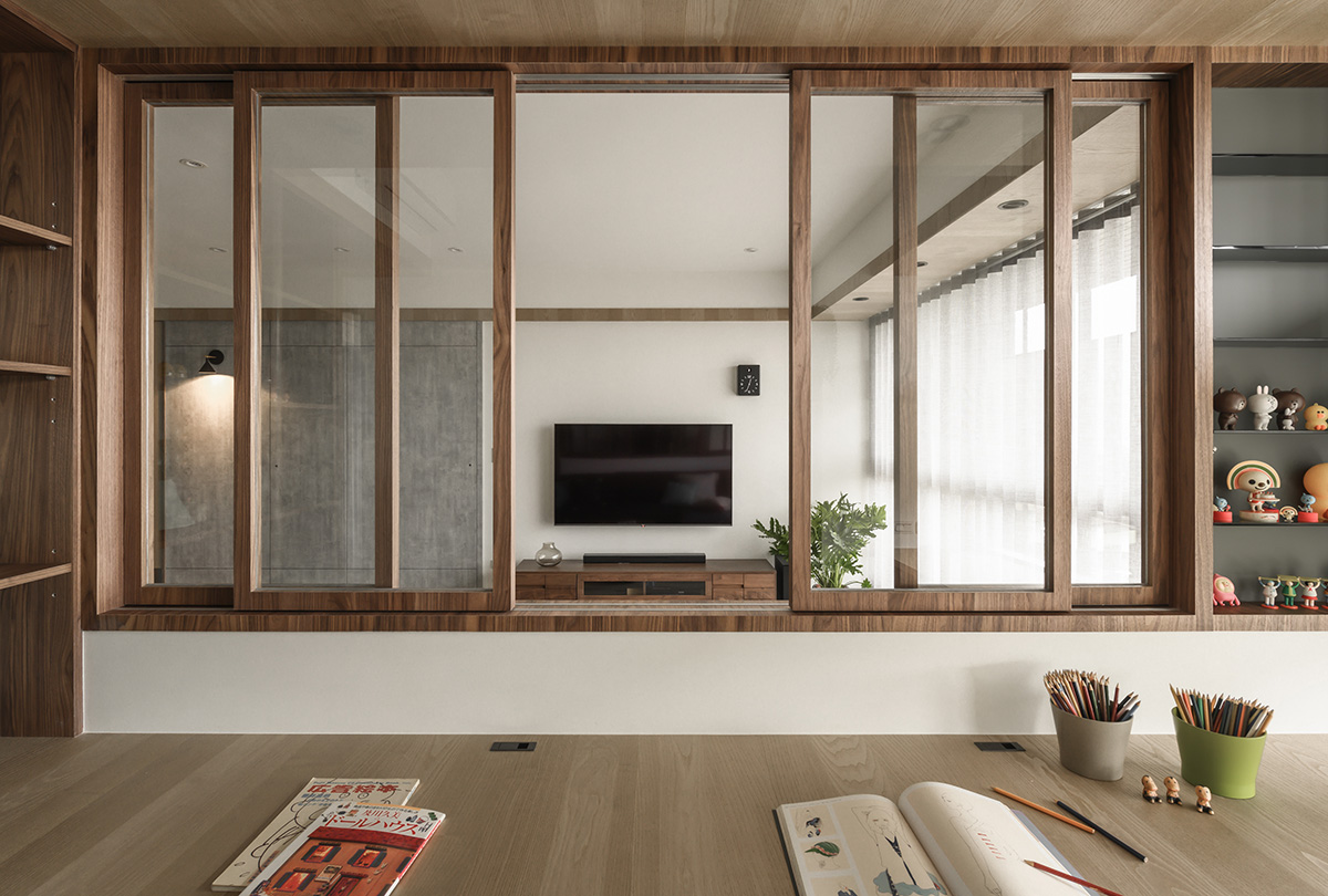 Khu vực bức tường sau ghế sofa phòng khách được kết hợp với một nửa tường kính kiểu cửa trượt khung gỗ để tạo sự kết nối xuyên suốt với phòng làm việc và học tập phía sau. Giải pháp này cũng giúp cho không gian tận dụng tối đa nguồn ánh sáng.