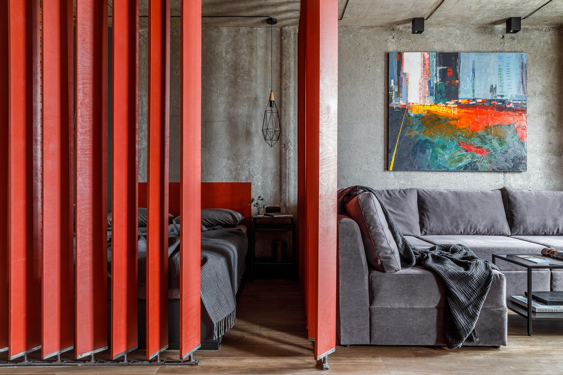 Căn hộ nhỏ thiết kế theo phong cách công nghiệp với sàn lát gỗ mộc, trần và tường bê tông thô, trong đó phòng ngủ được phân vùng bằng những thanh ván ép dọc xoay 360 độ cá tính với sắc đỏ cực kỳ nổi bật.