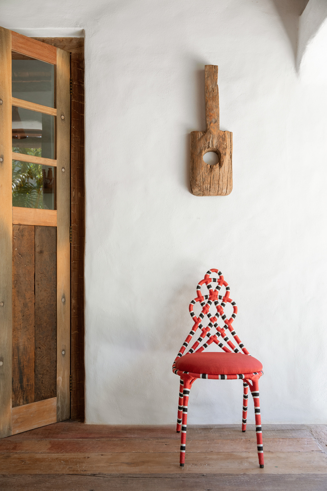 Bên trên chiếc ghế đỏ nổi bật quyến rũ ấy là một mảnh gỗ trang trí từ Trancoso của Divino.