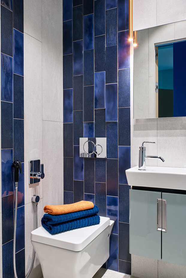 Phòng tắm và nhà vệ sinh được thiết kế trong cùng một không gian, bị giới hạn bởi diện tích chỉ vỏn vẹn vài mét vuông nhưng không vì thế mà mất đi sự lôi cuốn. Chỉ một vài viên gạch thẻ ốp dọc bức tường vừa cao vừa hẹp, thêm sắc xanh lam chuyển đổi đậm - nhạt xen kẽ trông 'chất' vô cùng.