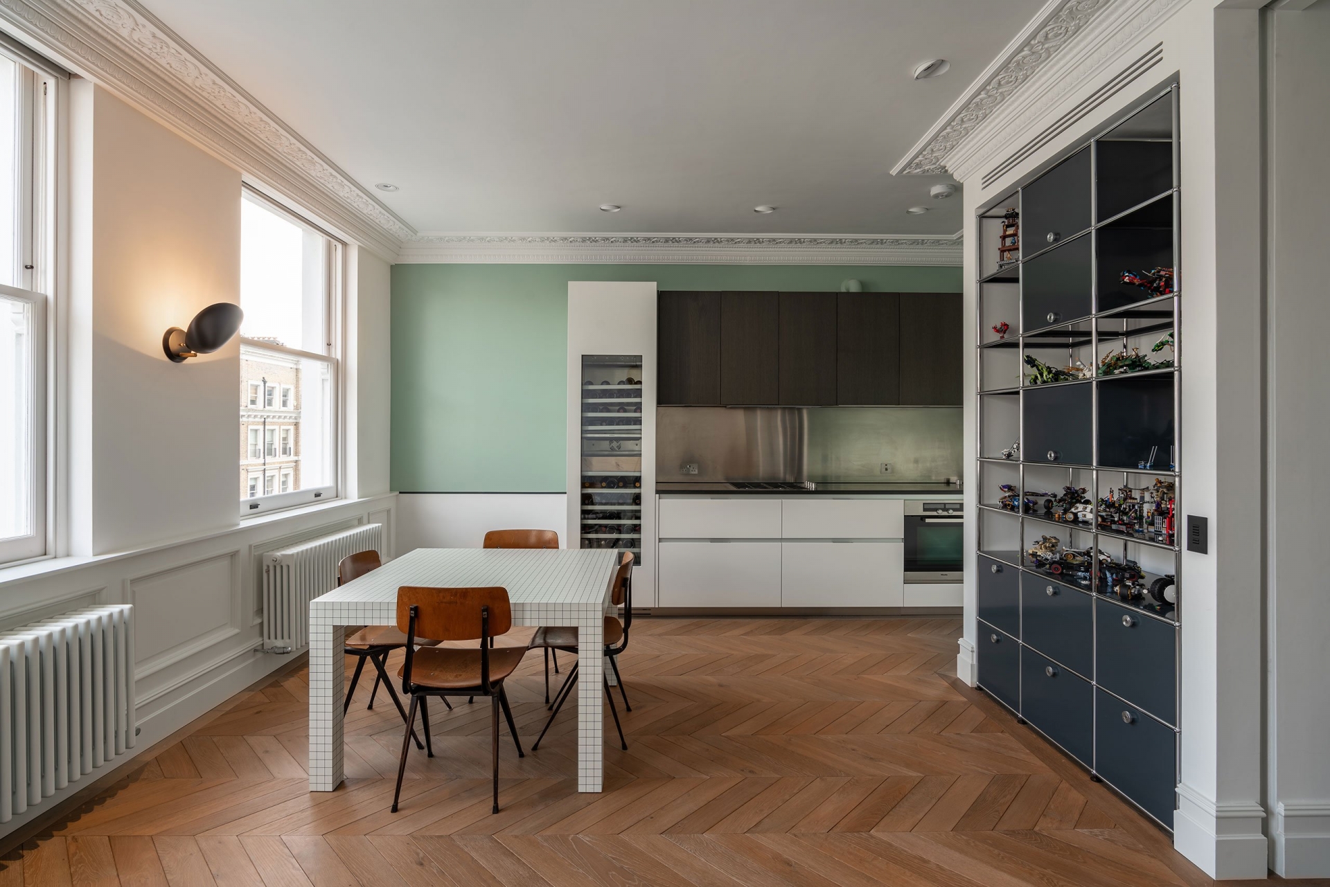 Một phòng bếp kiểu chữ I nhỏ gọn trên nền tường màu xanh lá cây nhạt cho vẻ đẹp trang nhã, bên cạnh là tủ đựng rượu với rất nhiều loại phong phú. 