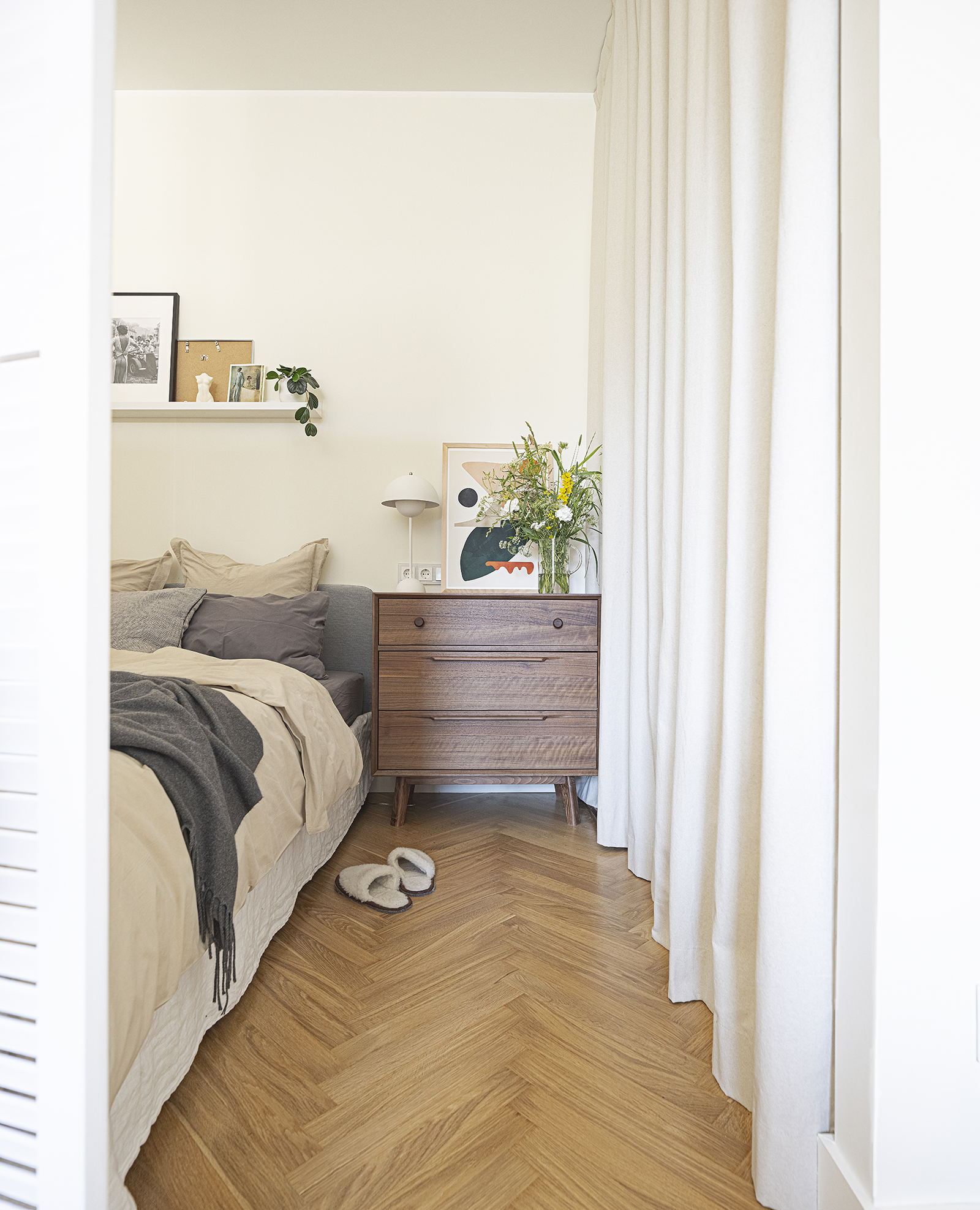 Phòng ngủ sau bức bình phong kiểu cửa chớp thiết kế tối giản, chỉ gồm một chiếc giường, kệ mở thanh lịch để trang trí và một chiếc táp đầu giường vuông vức. Tất cả nội thất gỗ trong nhà đều được làm từ gỗ óc chó hoặc gỗ sồi sang trọng.