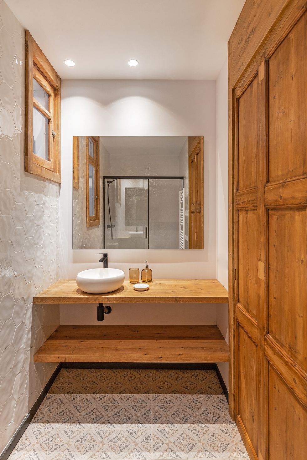 Trong phòng tắm, những cánh cửa, khung cửa gỗ tự nhiên được xếp liền với gạch lục giác sáng bóng ốp tường cùng bồn rửa hình bầu dục bằng sứ.