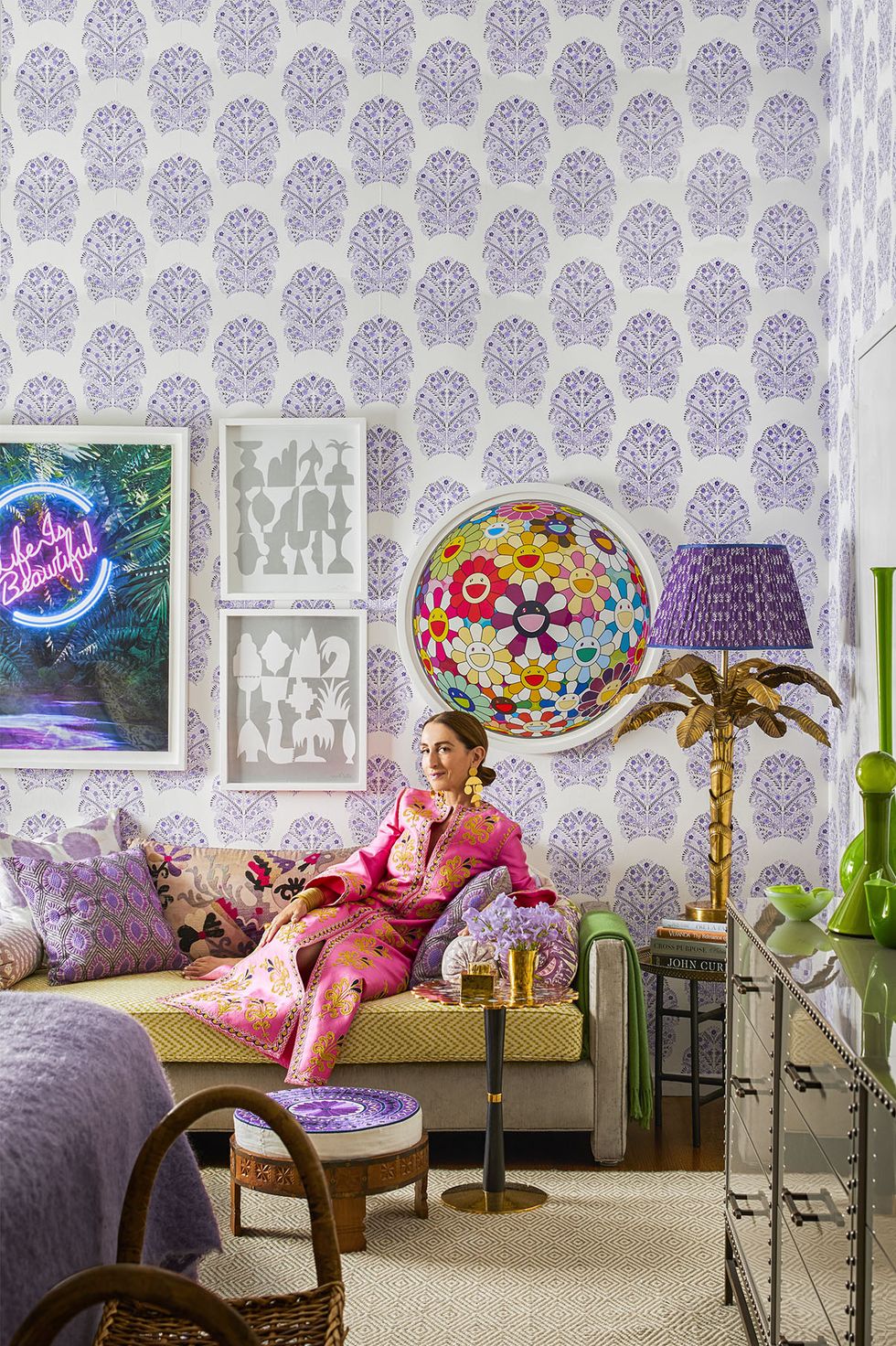 NTK thời trang Christina Juarez đang thả dáng tại phòng khách trong căn hộ của mình. Căn phòng rực rỡ sắc màu từ nội thất đến phụ kiện, hấp dẫn nhất có lẽ là giấy dán tường hoa văn tím trắng cùng một loại điểm nhấn trang trí đồng màu xung quanh.
