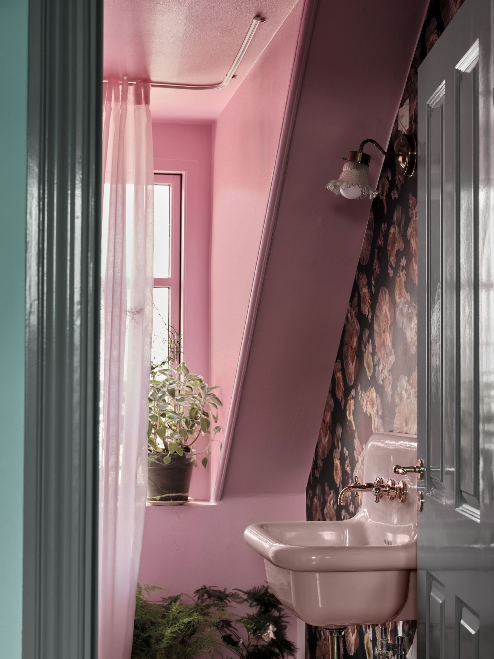 Thay vì sắc trắng quen thuộc, phòng tắm này lựa chọn sơn màu hồng cùng giấy dán tường hoa văn nữ tính, kết hợp vài chậu cảnh tươi xanh cho người yêu vẻ ngọt ngào.