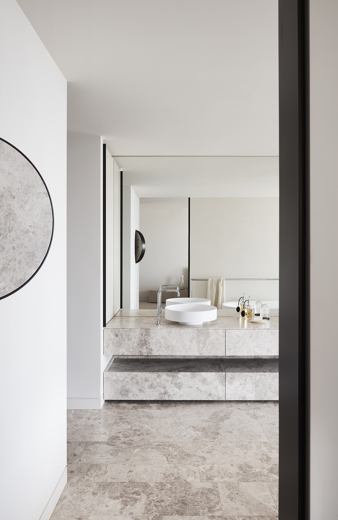 Tương tự như thiết kế phòng bếp, khu vực phòng tắm cũng sử dụng vật liệu đá tự nhiên để lát toàn bộ phần sàn nhà và tủ vanity (tủ kết hợp bồn rửa) sang chảnh. Tấm gương khổ lớn ốp kín bức tường cũng giúp 'nhân đôi' không gian một cách trực quan.