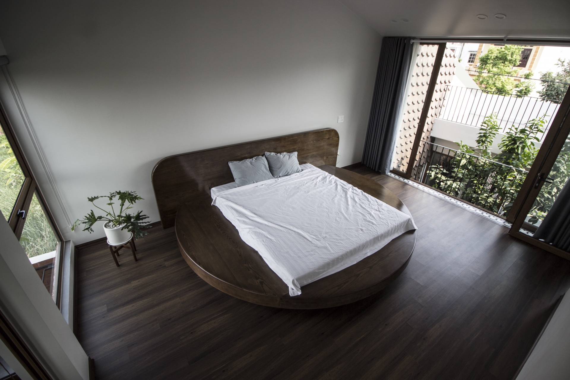 Phòng ngủ tối giản với chiếc giường tròn bằng gỗ đa năng: Vừa là giường, vừa là ghế ngồi xem tivi, kiêm cả chức năng của táp đầu giường tiện lợi.