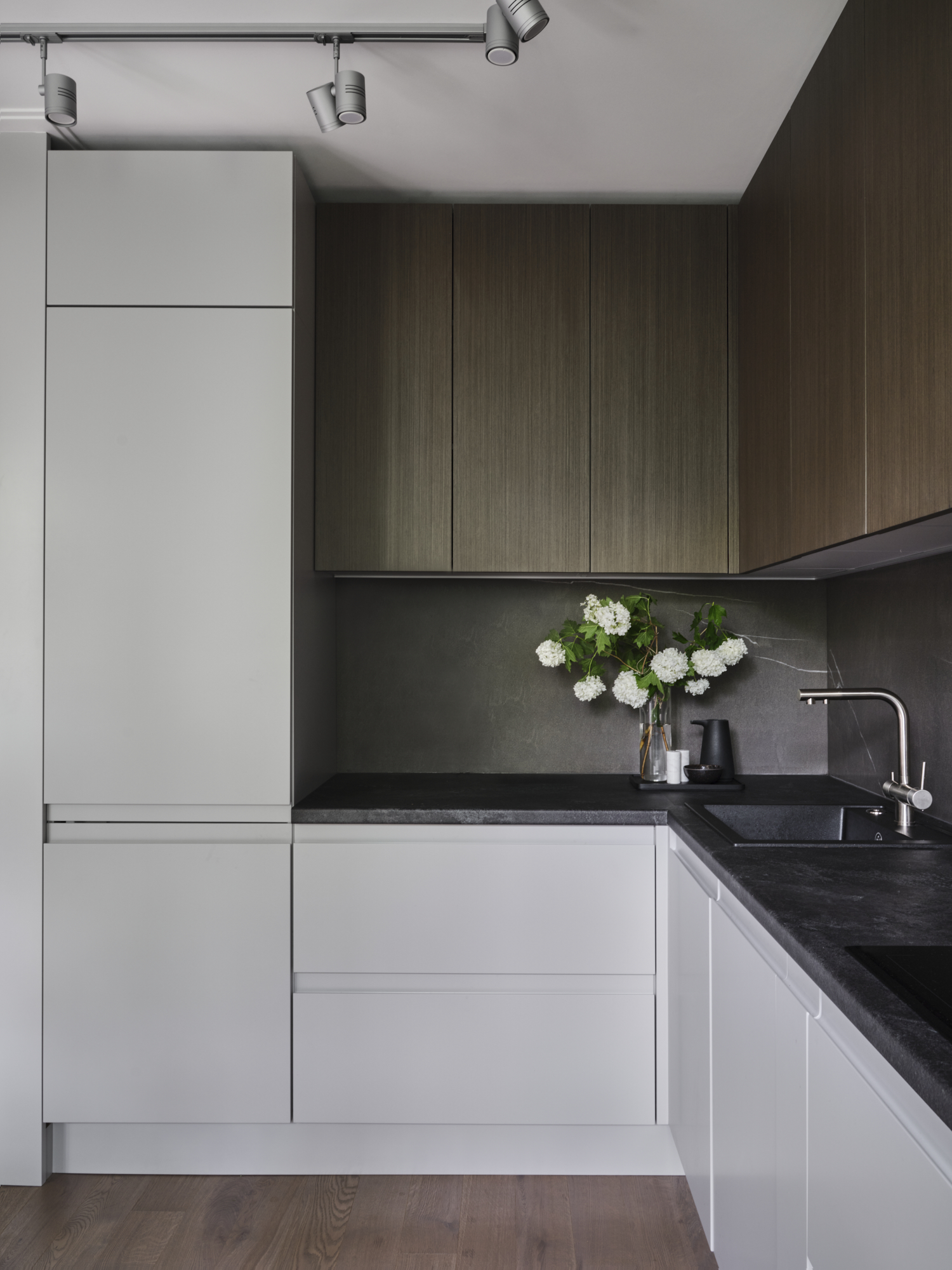 Phòng bếp thiết kế kiểu chữ L phù hợp với cấu trúc căn hộ nhỏ, thêm vào đó là sự tương phản của hệ tủ bếp màu gỗ trầm ấm và hệ tủ dưới sắc trắng thanh lịch, sạch sẽ càng thêm bắt mắt.