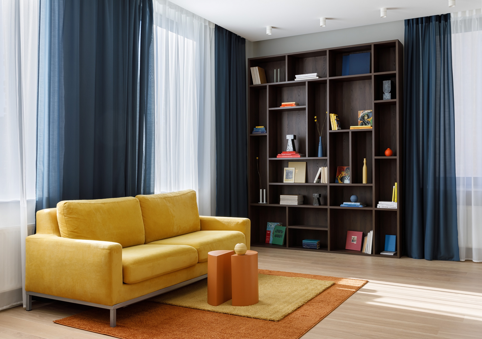 Phòng khách rộng rãi với ghế sofa được chuyển đến từ căn hộ cũ, tuy nhiên NTK đã chọn thay bọc vải mới có gam màu vàng tươi sáng. Lựa chọn này cũng rất 'tone sur tone' với bộ thảm trải sàn vàng - cam từ thương hiệu IKEA.