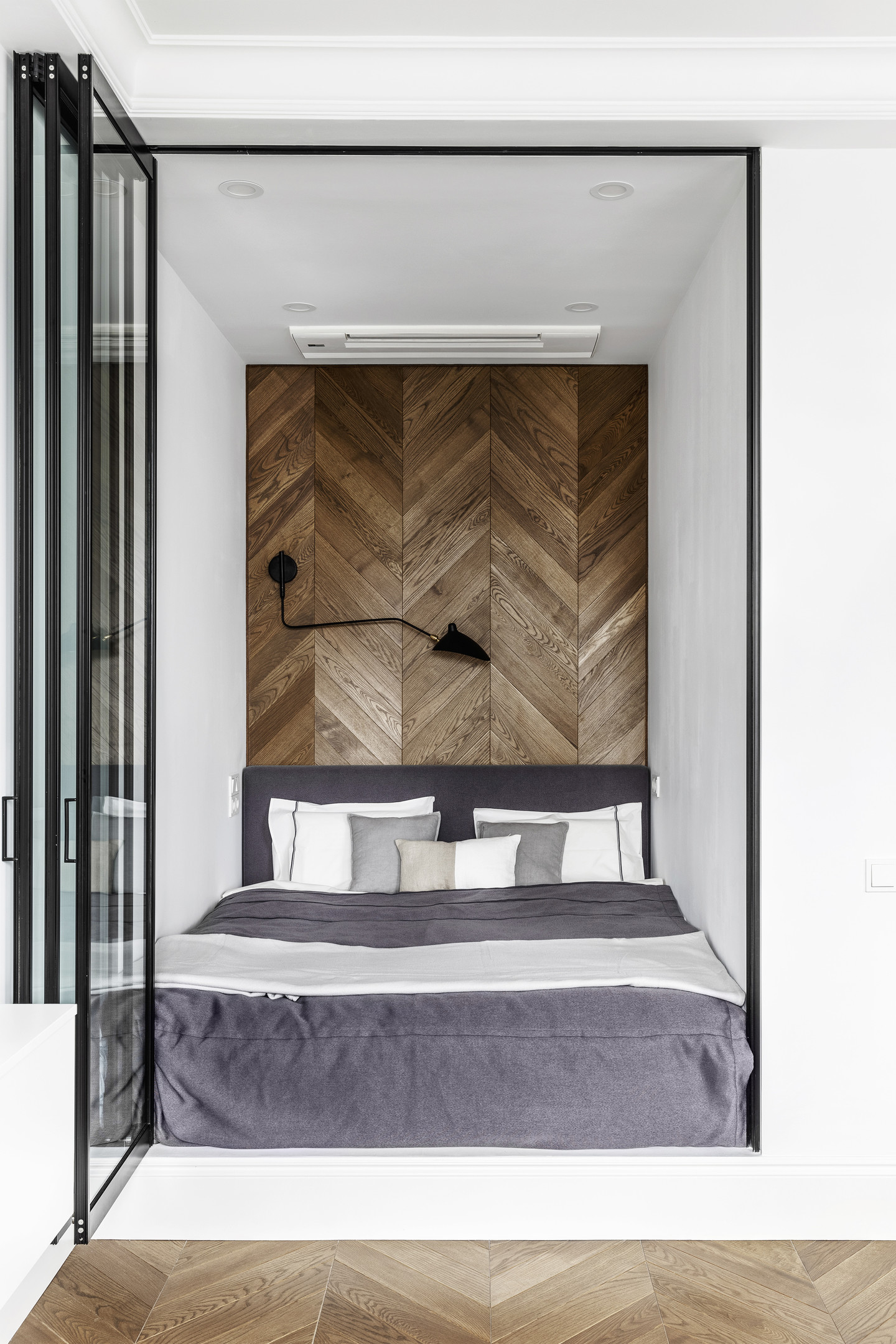 Căn hộ siêu nhỏ do Geometrium Design Studio thiết kế với phòng ngủ bố trí trong một hốc tường và sử dụng cửa kính trong suốt. Sự liên kết giữa gỗ lát sàn và gỗ ốp tường họa tiết xương cá tạo cái nhìn hài hòa đẹp mắt.