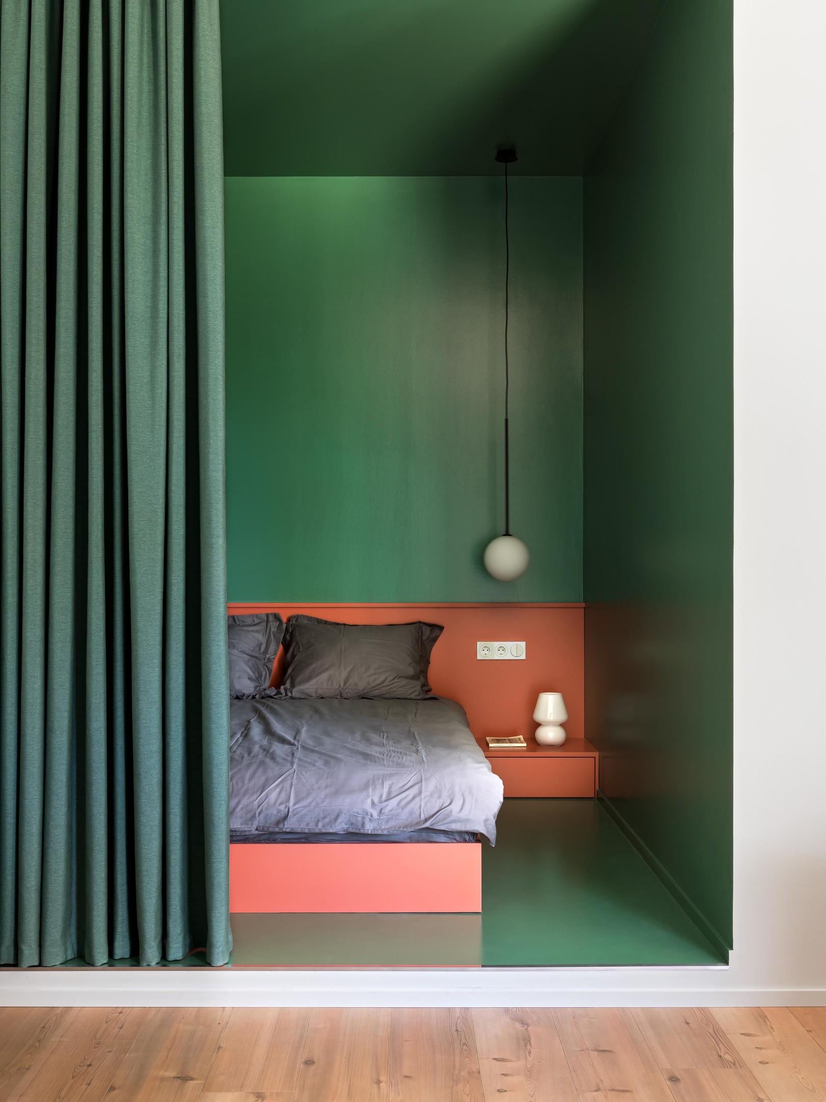 Căn hộ thiết kế bởi VAE Design studio với phòng ngủ ấn tượng, không chỉ nhờ tận dụng hốc tường mà còn sử dụng màu xanh ngọc lục bảo thời thượng. Một chút nhấn nhá từ sắc cam gạch ở khu vực đầu giường cho phòng ngủ nhỏ càng nổi bật.