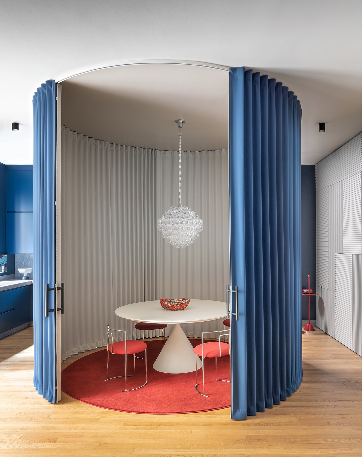 Căn hộ tại Milan (Ý) do Calvi Brambilla Studio thiết kế. Phòng ăn được 'bao bọc' bởi hệ khung hình trụ có rèm kéo của thương hiệu Dooor. Lớp bên trong màu trắng, lớp bên ngoài màu xanh lam 'tone sur tone' với hệ tủ bếp.