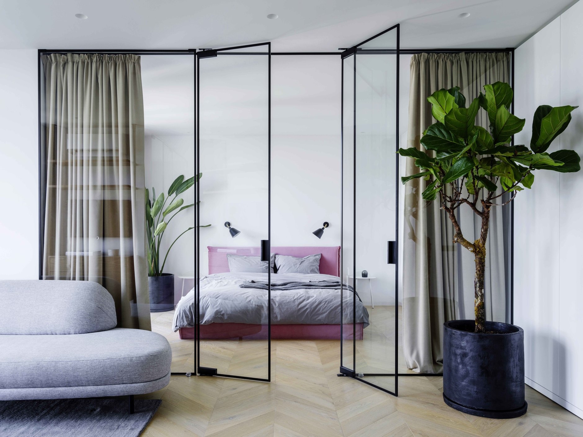 Dự án của Iya Turabelidze với không gian phòng ngủ được phân tách với phần còn lại của căn hộ bằng cấu trúc kính trong suốt kết hợp rèm che dày dặn để tạo sự riêng tư. Vào ban ngày, rèm được mở để ánh sáng thông suốt không gian.