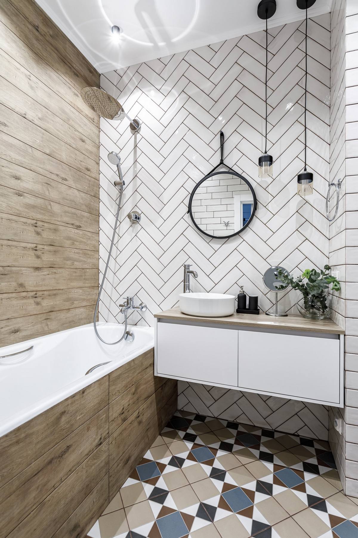 Phòng tắm nhỏ gọn với sàn nhà lát gạch tương tự lối vào nhà. Bức tường được chia thành 2 kiểu trang trí. Một bên ốp gỗ đã xử lý chống thấm, một bên ốp gạch màu trắng bóng. Tủ vanity gắn tường được lựa chọn giúp giải phóng diện tích mặt sàn.