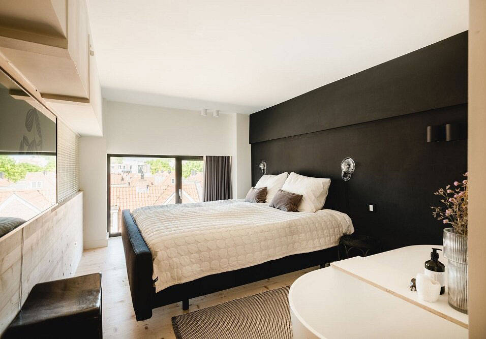 Phòng ngủ chính của bố mẹ với 2 tone màu trắng - đen cổ điển, đối lập giữa trần nhà, tường cửa sổ và khu vực đầu giường cho vẻ đẹp sang chảnh.