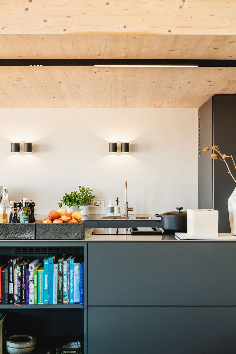 Phòng bếp thiết kế đơn giản, gọn gàng và tươi sáng với hệ thống đèn gắn tường và đèn trần tạo hiệu ứng đẹp mắt trên bức tường trắng. 