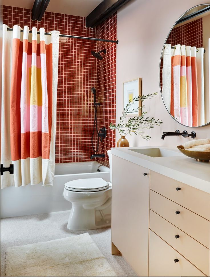 Bí quyết của sự bắt mắt là một bảng màu hấp dẫn và phòng tắm này đã chứng minh điều đó! Màu đỏ mận của gạch ô vuông nhỏ ốp tường, tấm rèm che với những tone màu 'nóng' như hồng, cam, đỏ,... mang lại sự trẻ trung, ấm áp cho phòng tắm nhỏ.