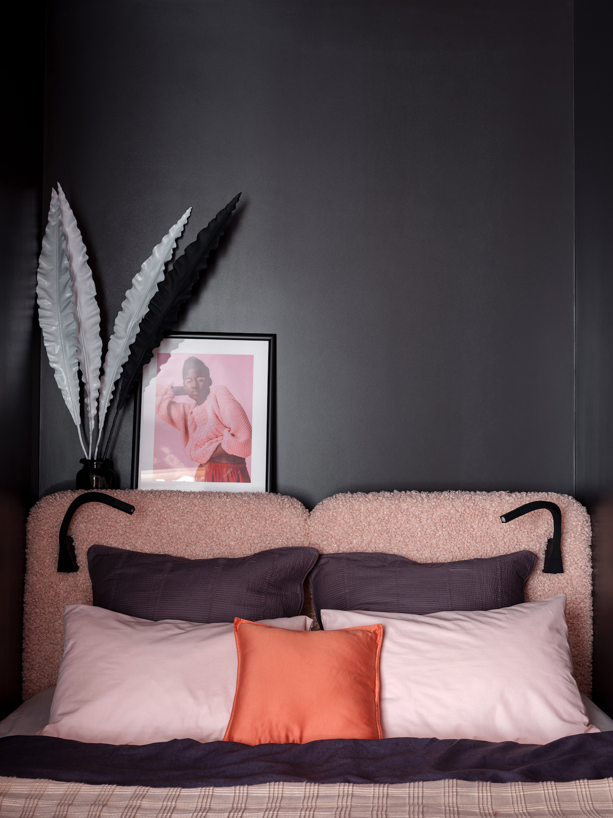 Nếu bên ngoài 'ốc đảo' riêng tư được sơn màu tím quyền lực thì bên trong tường phòng ngủ lại chọn màu xám đen cá tính. Trên phông nền tối đậm ấy, những gam màu yêu thích như hồng phấn, tím, cam san hô lại trở nên vô cùng nổi bật và ấm áp.