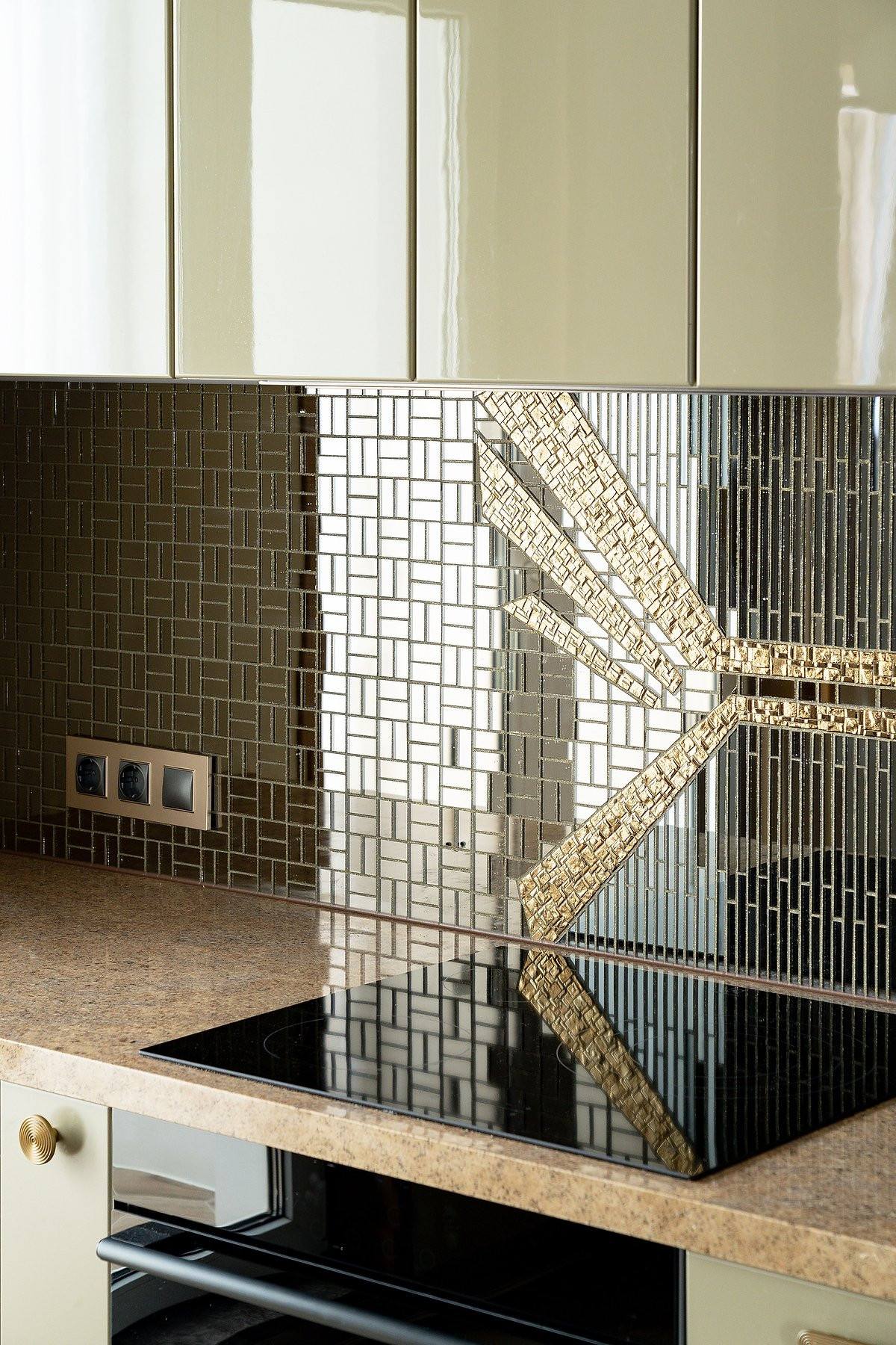 Ngoài ra, khu vực backsplash thiết kế theo phong cách Art Deco với những viên gạch tráng gương được thiết lập khéo léo, thêm những chi tiết mạ vàng đồng tạo nên sự sinh động như một tác phẩm nghệ thuật trong bếp nhỏ.