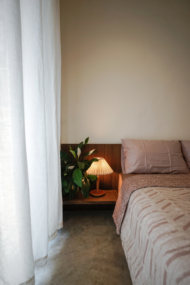 Phòng ngủ dành cho khách cũng được chăm chút từng chi tiết nhỏ, từ bộ chăn ga gối màu hồng đỗ nhẹ nhàng cho đến cây cảnh trang trí và đèn ngủ đặt trên táp đầu giường nhỏ xinh.